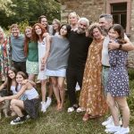 A family portrait taken outside of a stone house, with several generations of individuals.