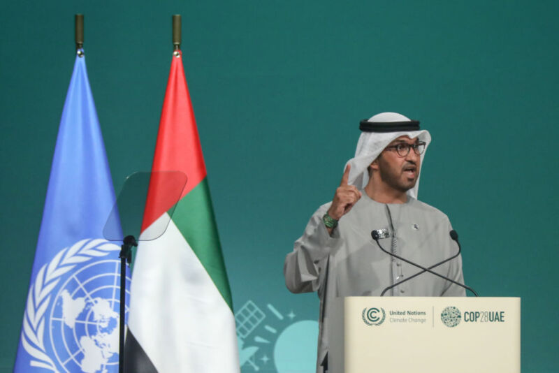 Image of a man wearing traditional clothing gesturing while speaking at a podium.