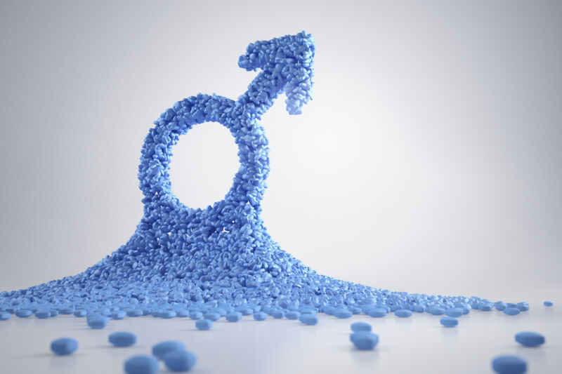 Image of a pile of blue pills that forms the shape of a male symbol.