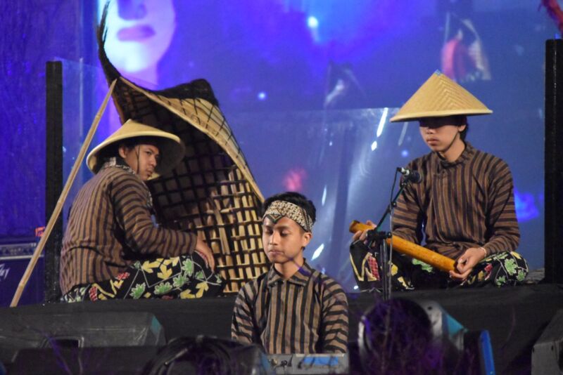 Artistas indonesios en el escenario y uno de ellos tocando un bundengan.