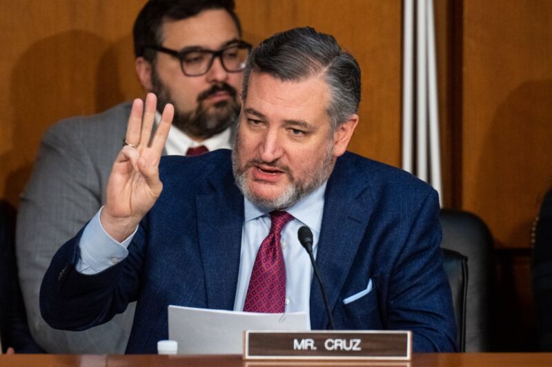 Sen. Ted Cruz speaks at a Senate committee hearing while holding up three fingers.