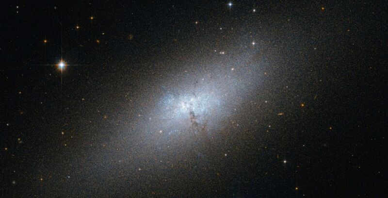 A diffuse cloud of light extending from lower left to upper right, sitting in a field of stars.