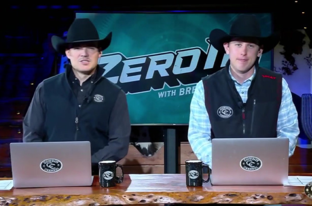 two young guys in cowboy hats with laptops against a studio backdrop