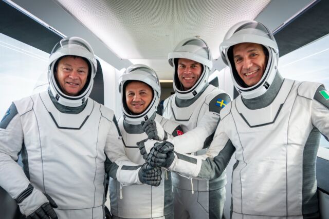 Michael Lopez-Alegría, Albert Geseraphci, Markus Wandt, and Walter Velade stand inside the SpaceX crew access arm at Launch Complex 39A in Florida.