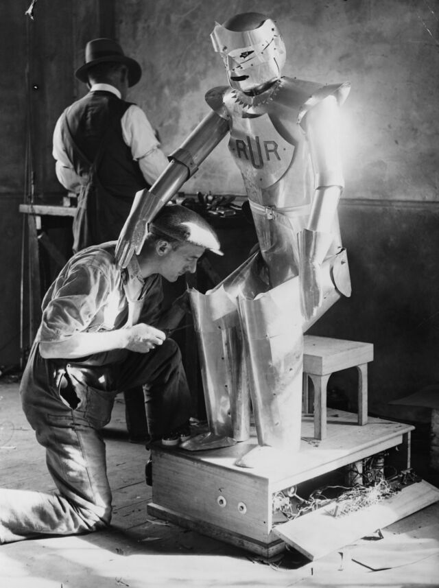 "Um assistente do inventor Capitão Richards trabalha no robô que o Capitão inventou, que fala, responde perguntas, aperta a mão, diz as horas e senta quando é mandado." - setembro de 1928
