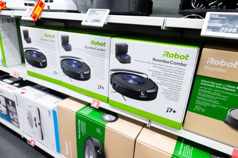 A store shelf holds several boxes that contain Roomba vacuum cleaners.
