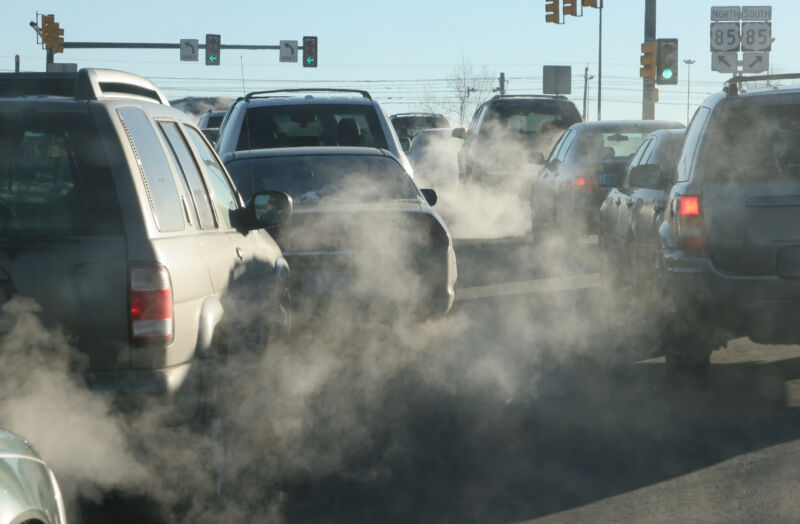 En una intersección en Denver, Colorado, los gases de escape salen de los tubos de escape de los vehículos que aceleran hacia Santa Fe Drive.