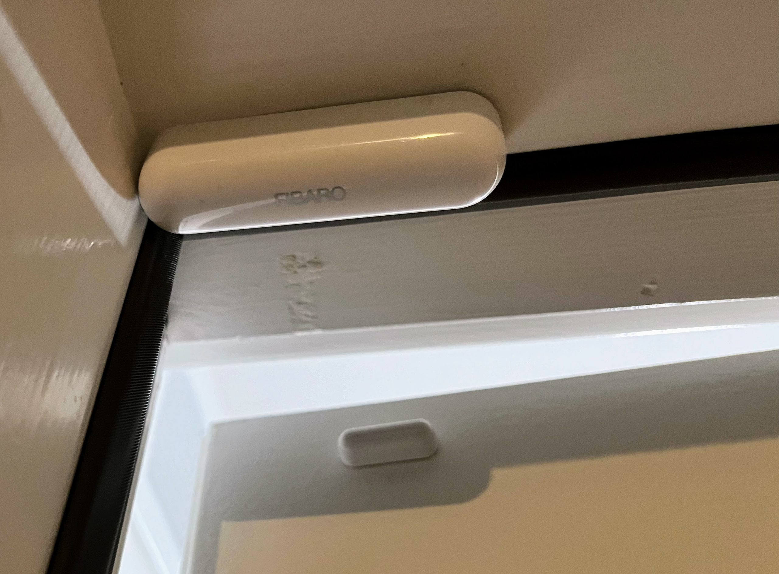 Fibaro door sensor mounted above a white door.