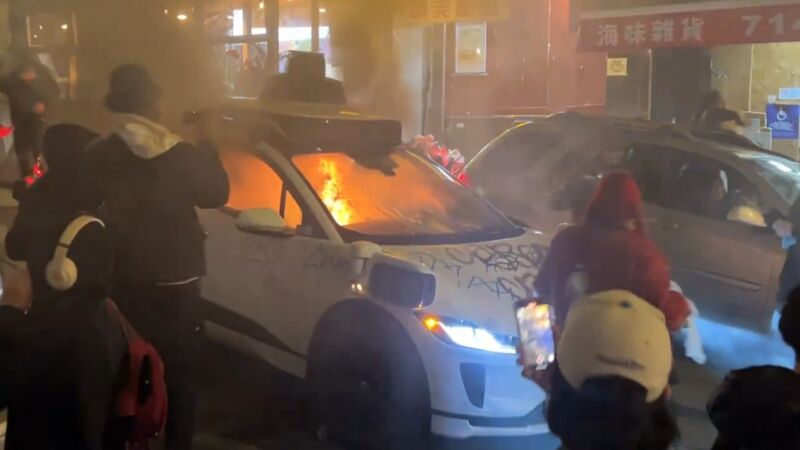 A fire starts inside a Waymo car after a vandal threw a lit firework through the window. 