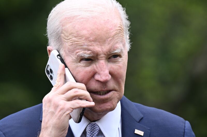 President Joe Biden holding a cell phone to his ear while he talks.