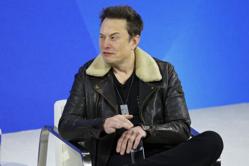 Elon Musk sits on stage while being interviewed during a conference.