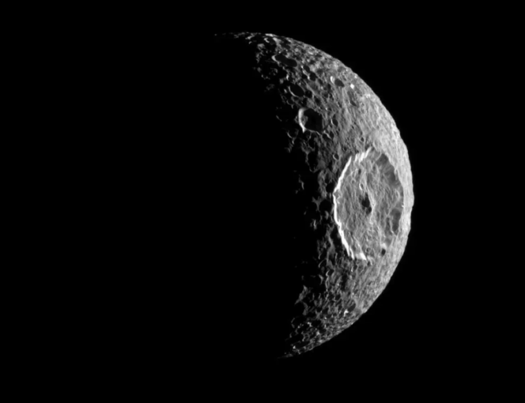 Greyscale image of a moon lit on one side, with its face dominated by a giant crater.