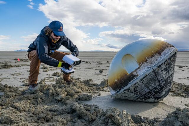 A member of Varda's recovery team inspects the reentry capsule.