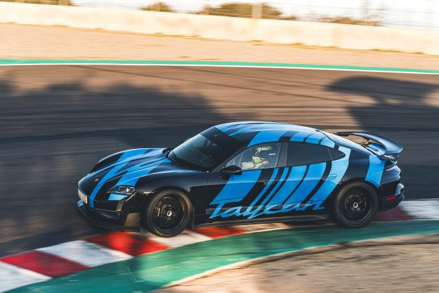 A black Porsche with blue decals drives on track