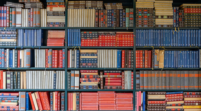 Un conjunto de estanterías de biblioteca con muchos volúmenes apilados sobre ellas.