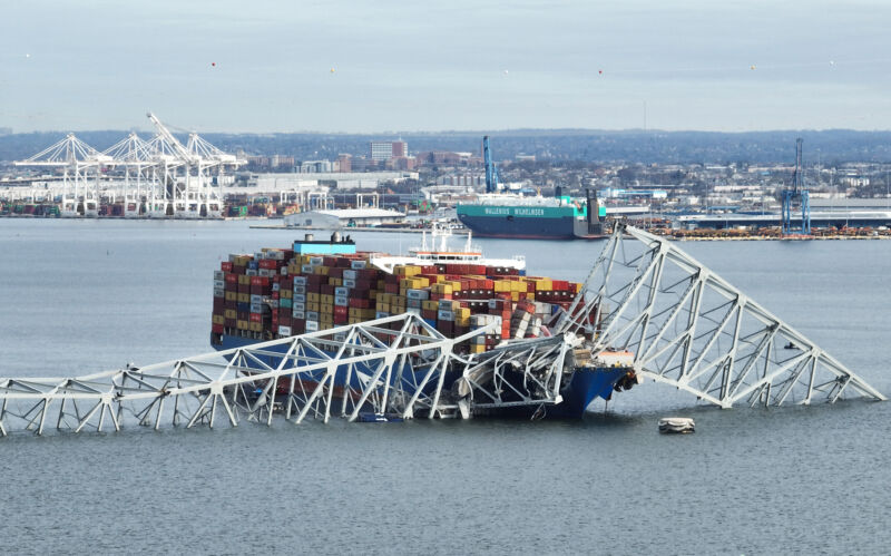 The steel frame of the Francis Scott Key Bridge sits on top of a container ship after the bridge collapsed in Baltimore.