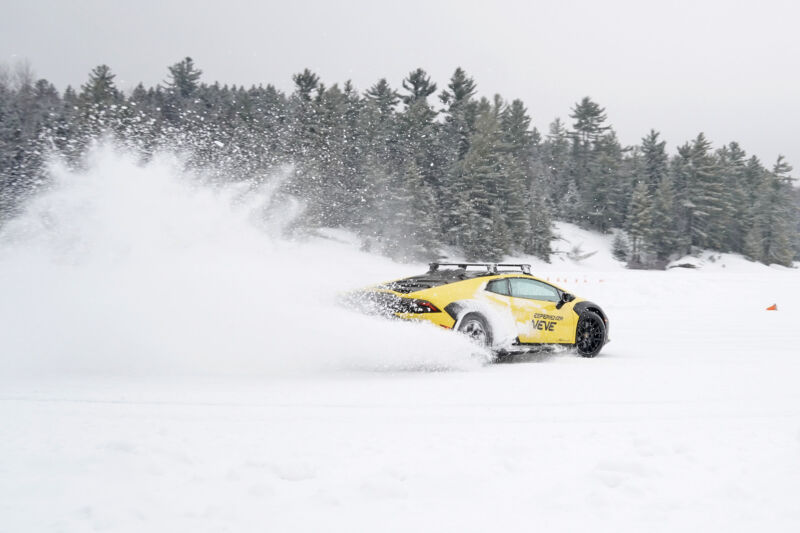 A yellow lamborghini huracan sends up a spray of snow as it drives on a frozen lake