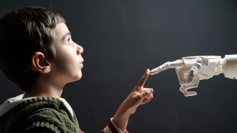Un niño en edad de escuela primaria tocando la mano de un robot.