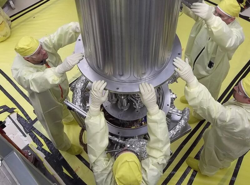 Engenheiros da NASA e da Administração Nacional de Segurança Nuclear baixam a parede de uma câmara de vácuo em torno do experimento KRUSTY, um reator de quilowatts que usa tecnologia Stirling.