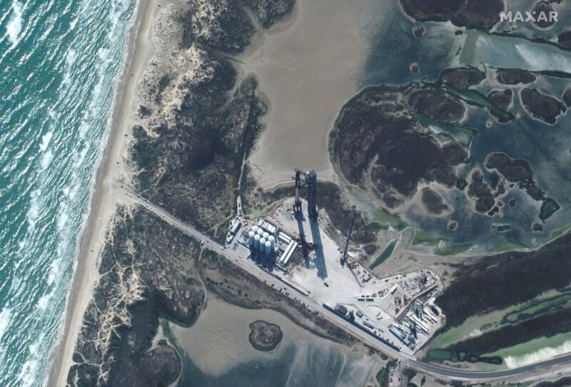 Esta vista satelital de las instalaciones Starbase de SpaceX muestra un cohete Starship completamente apilado en la plataforma de lanzamiento, tierra adentro desde el Golfo de México.
