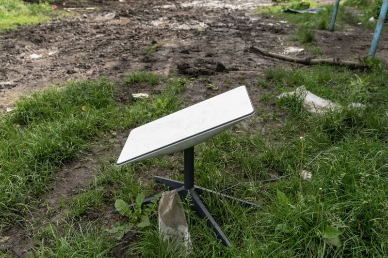 Una antena parabólica Starlink se encuentra en el suelo afuera.