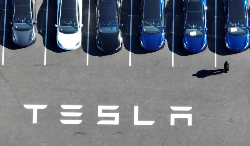 Aerial view of Tesla cars in a parking lot at a Tesla facility.