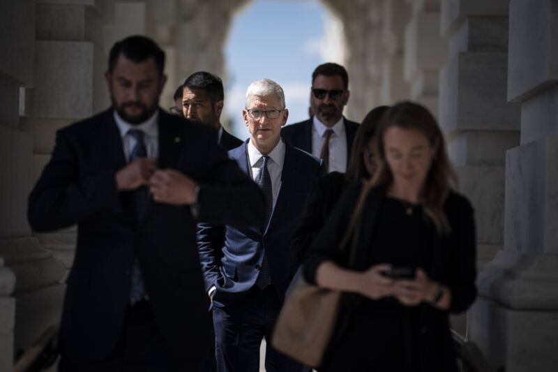 El director ejecutivo de Apple, Tim Cook, y otras personas caminan por un arco al salir del edificio del Capitolio de Estados Unidos.