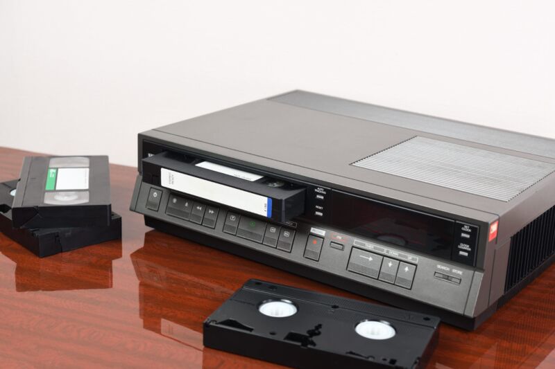 VHS tapes are pictured along with a vintage VCR device from the 1980s