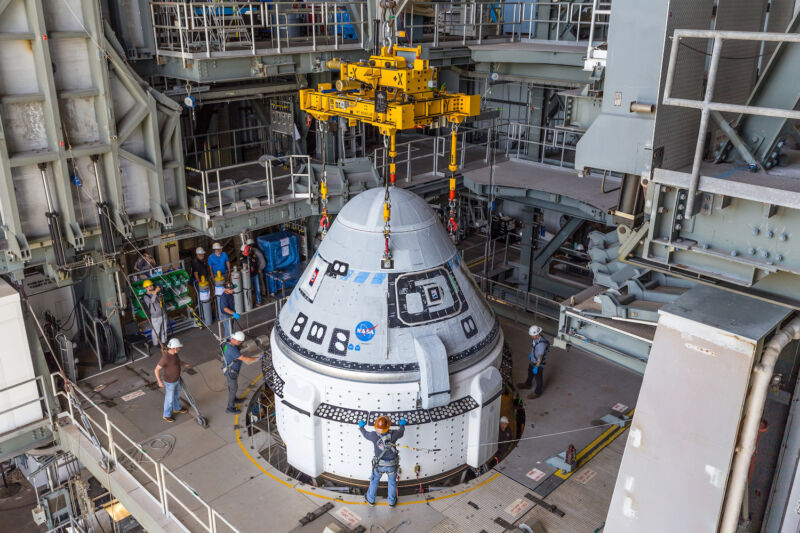 Los técnicos dentro de la Instalación de Integración Vertical de United Launch Alliance conectan la nave espacial Starliner de Boeing con la parte superior de su cohete Atlas V el martes.