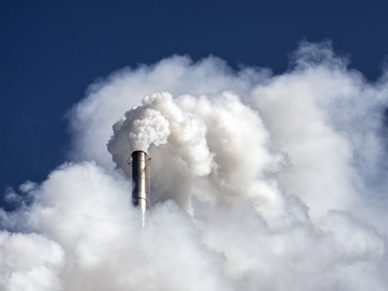 Image of a cloud of white smoke erupting from a large, metal smokestack.