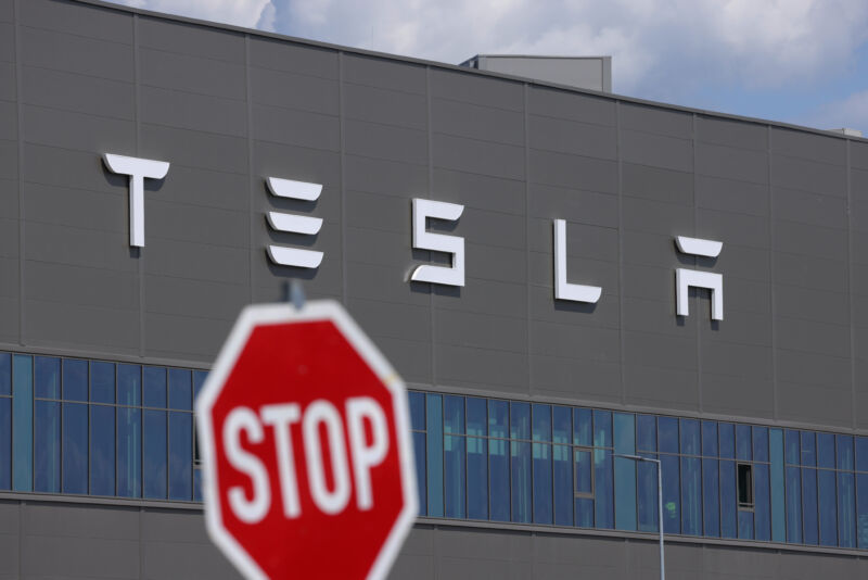 GRUENHEIDE, GERMANY - JULY 17: A stop sign stands near the Tesla logo at the Tesla factory on July 17, 2023 near Gruenheide, Germany. Tesla will reportedly present its plans tomorrow to expand production at the factory, from thee current level of approximately 250,000 cars per year to one million. The plan calls for the construction of a new assembly hall that will be the size of 60 soccer fields, which is likely to draw opposition from local communities. (Photo by Sean Gallup/Getty Images)