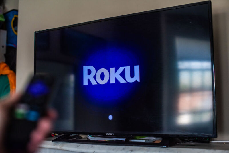 Logotipo de Roku en el televisor con control remoto en primer plano