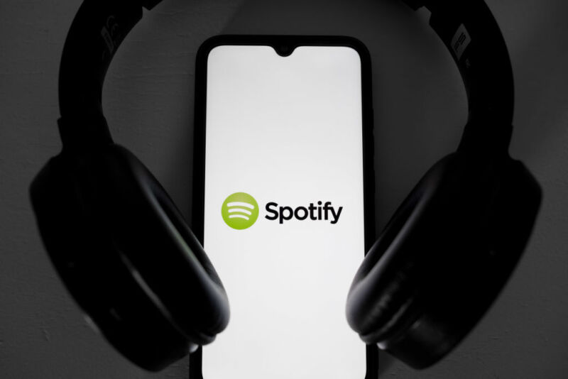 Logotipo de Spotify en la pantalla del teléfono con auriculares alrededor del teléfono