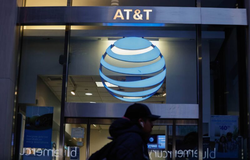 A person walks past an AT&T store on a city street.