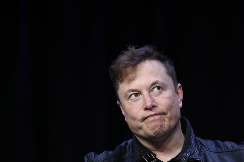 Elon Musk frunce el ceño mientras está sentado en el escenario durante una entrevista en una conferencia.