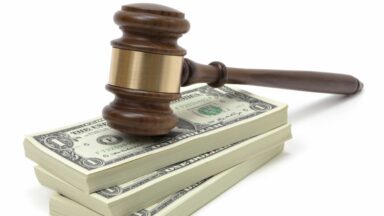 A judge's gavel resting on a pile of one-dollar bills