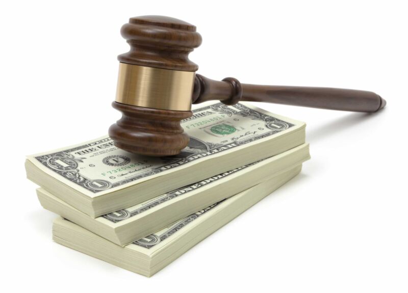 A judge's gavel rests on a pile of one-dollar bills