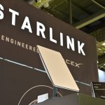 A Starlink terminal in front of a sign that says, "Starlink: Engineered by SpaceX."