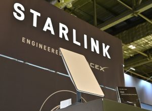 A Starlink terminal in front of a sign that says, "Starlink: Engineered by SpaceX."