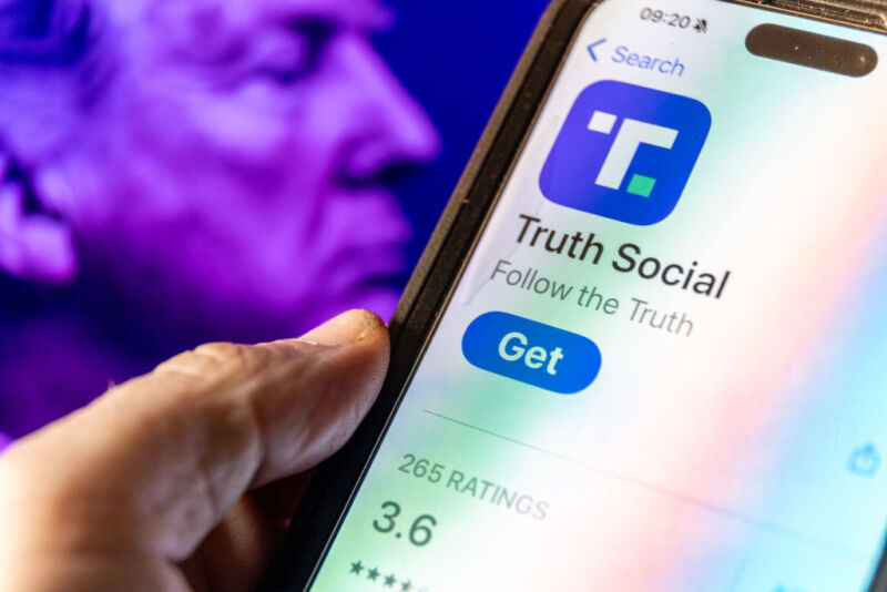 person holding phone with icon for Truth Social visible