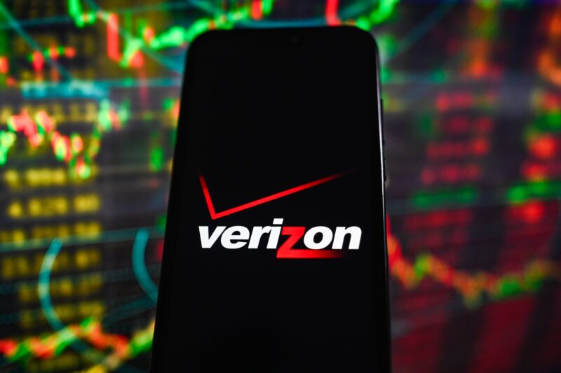 Illustration with a Verizon logo displayed on a smartphone in front of stock market percentages in the background.