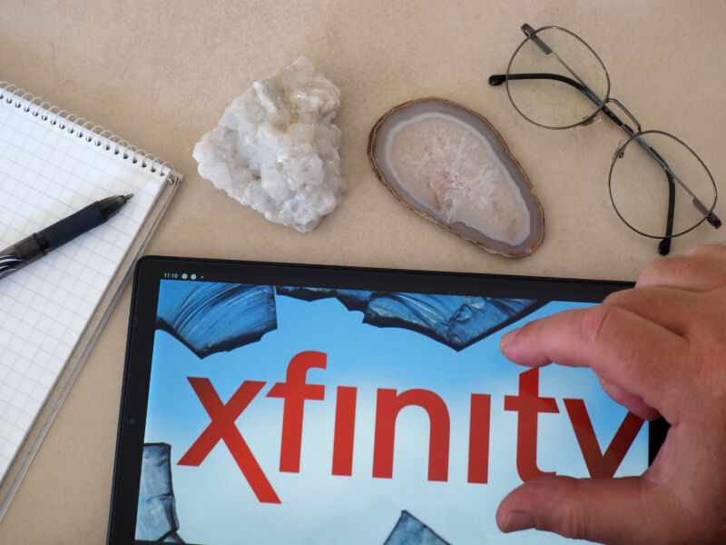 Xfinity log on a tablet, with fossil rocks, glasses, and a notepad on the desk beside it.