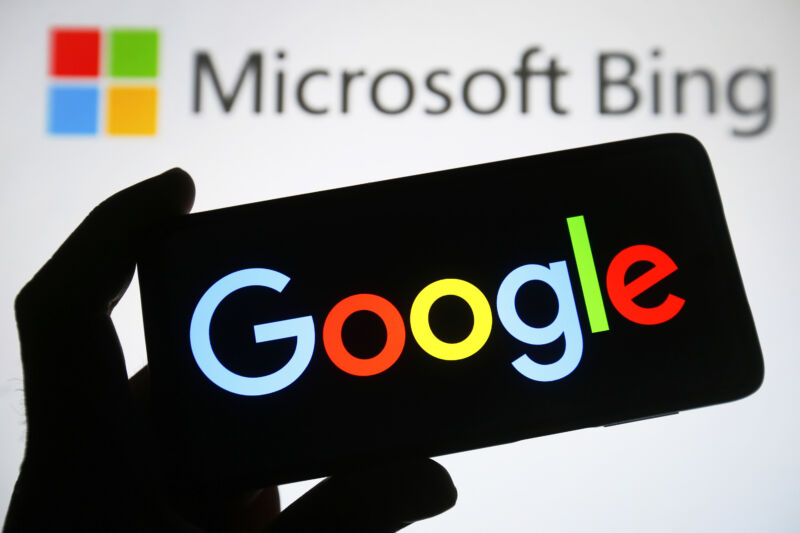 Logotipo de Google en un teléfono frente a un logotipo de Bing al fondo