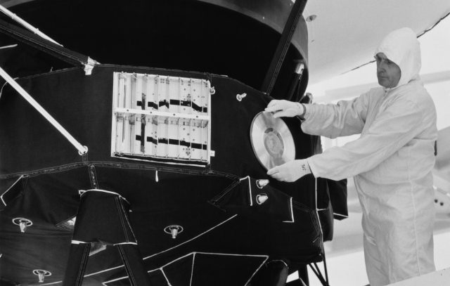 A technician attaches a gold record to a Voyager space probe, USA, circa 1977. Voyager 1 and its identical sister craft Voyager 2 were launched in 1977 to study the outer Solar System and eventually interstellar space. The record, entitled 'The Sounds Of Earth' contains a selection of recordings of life and culture on Earth. The cover contains instructions for any extraterrestrial being wishing to play the record.