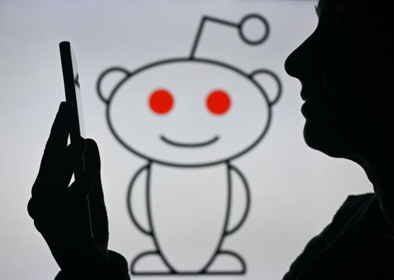 An image of a woman holding a cell phone in front of the Reddit logo displayed on a computer screen, on April 29, 2024, in Edmonton, Canada.