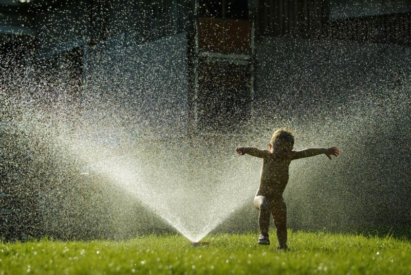  A child cools off under a water sprinkler.