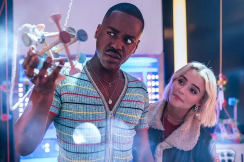 black man and pretty blonde woman examining a strange contraption