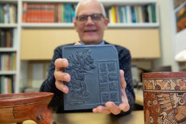 David Lentz holds up a sculpture that bears reproductions of ancient Maya glyphs.