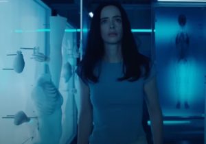 Young woman looking scared and confused in the middle of a creepy lab filled with synthetic body parts
