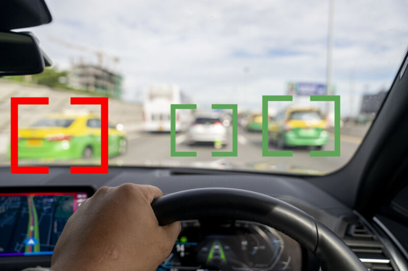 Image out the windshield of a car, with other vehicles highlighted by computer-generated brackets.